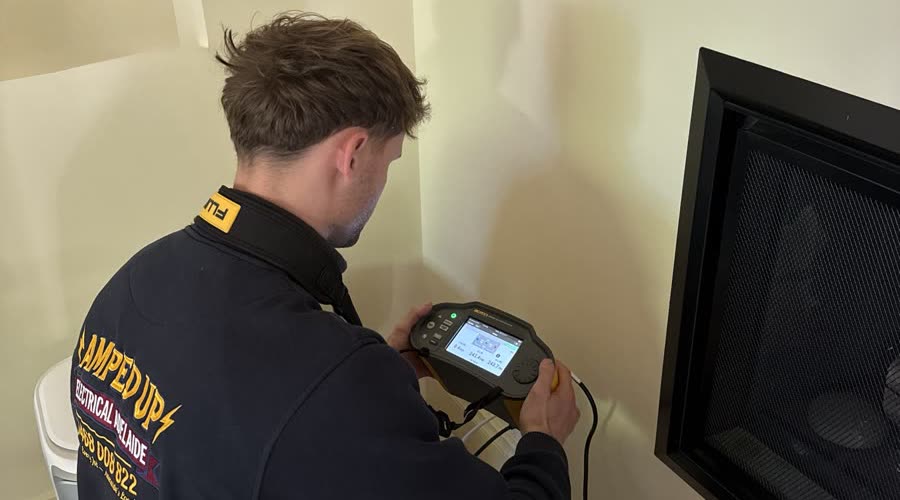 Marcus taking live test readings with a Fluke tester on an Adelaide job