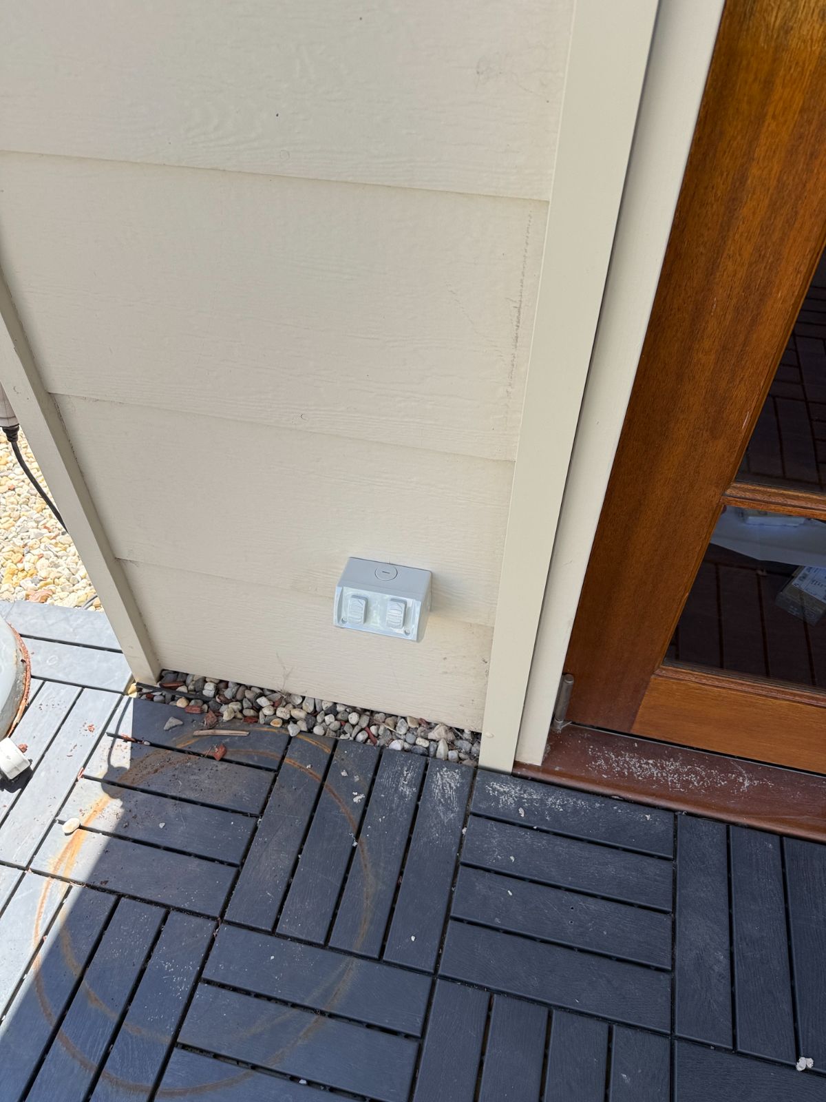 Weatherproof power point fitted to an outside wall above a timber deck