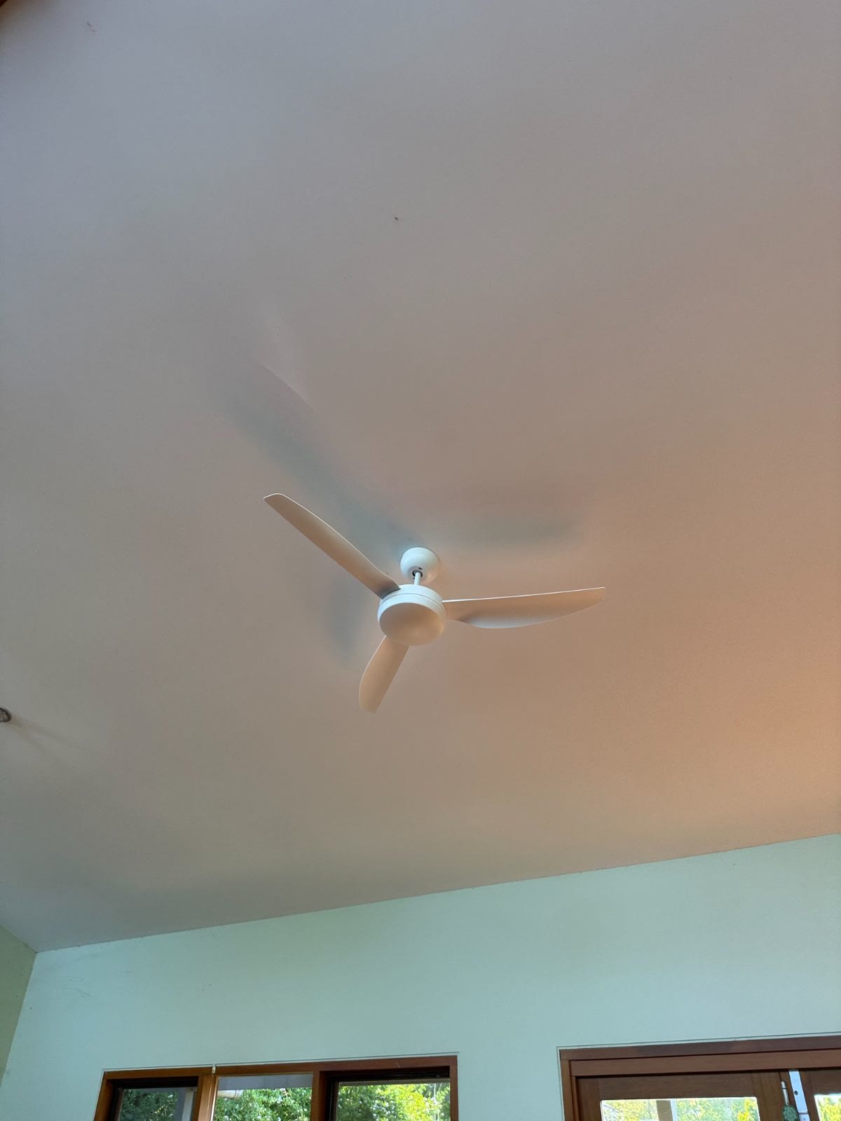 White three-blade ceiling fan installed under a high ceiling
