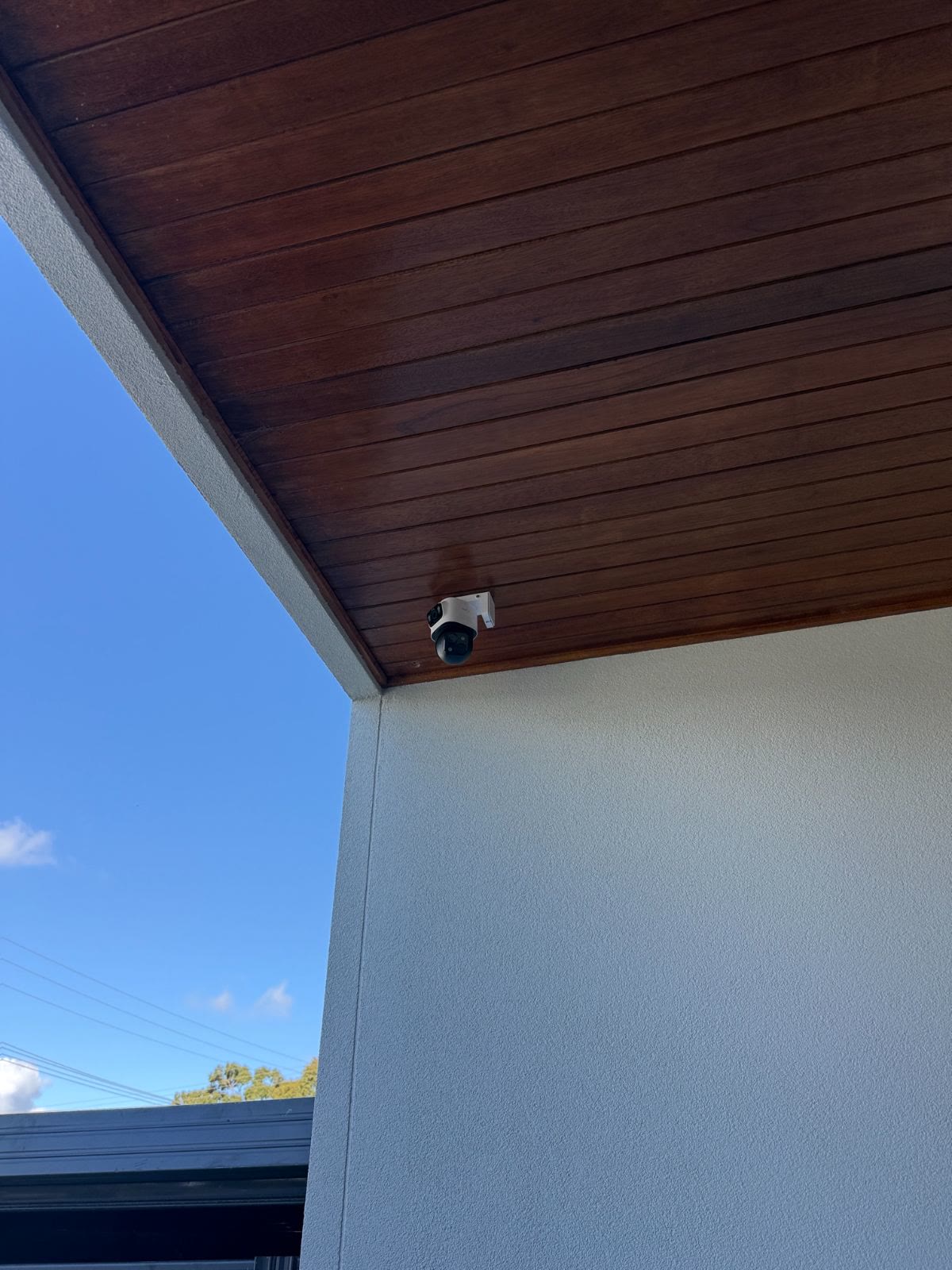Dual-lens camera on a bracket under a timber-lined eave