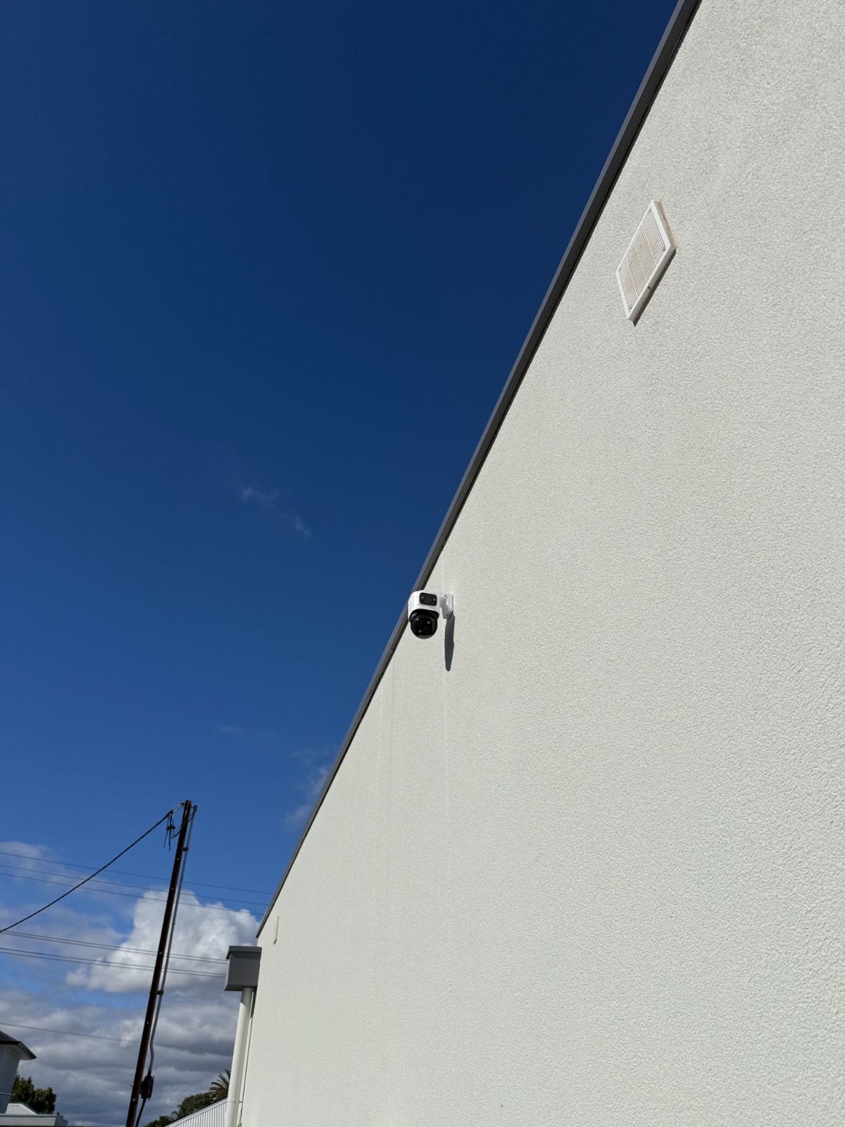 Dual-lens camera wall-mounted high on a rendered wall