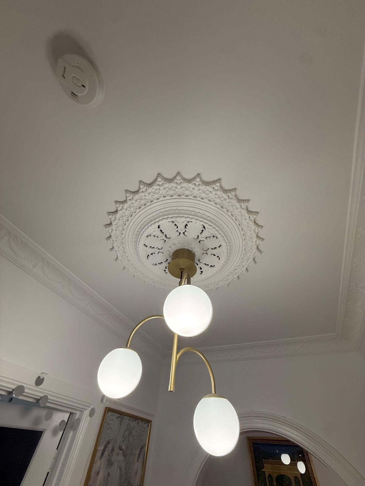 Gold three-globe pendant light under a ceiling rose